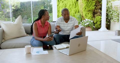 Couple Analyzing Financial Documents on Sofa
