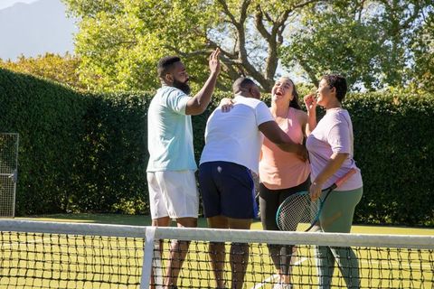 Diverse friends celebrating victory on tennis court