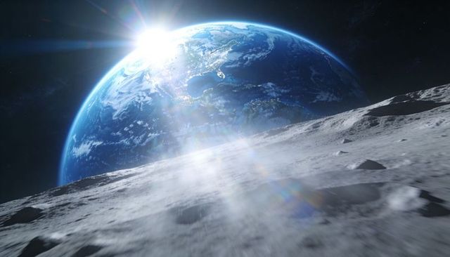 Earthrise over moon with sunflare casting blue glow across cratered surface