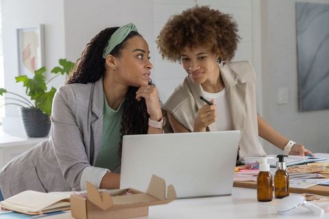African american women collaborating over laptop planning product packaging and branding