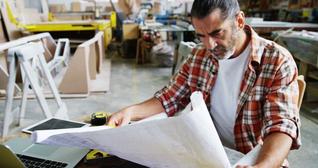 Middle-aged Craftsman Analyzing Blueprints in Workshop - Download Free Stock Images Pikwizard.com