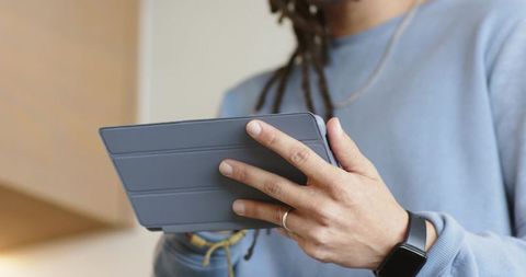 Mid adult man holding tablet in landscape wearing smartwatch and light blue sweatshirt