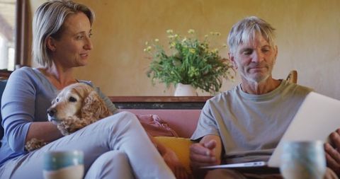 Senior Couple Relaxing with Dog Using Tablet at Home
