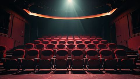 Spotlight illuminating luxurious red theater seats polished aisle