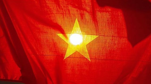 Backlit vietnam flag displaying glowing yellow star and textured red fabric
