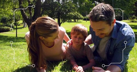 Parents leaning toward son on grass, bonding in sunlight with futuristic circuit overlay