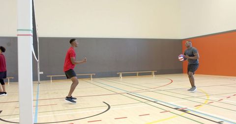 African american men practicing volleyball drill on indoor gym court for team training