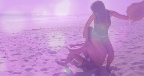 Joyful Couple Playing on Sunny Beach with Straw Hat