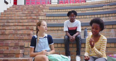 Diverse Friends Chatting on School Steps with Backpacks and Snacks
