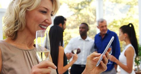 Middle-Aged Woman Enjoying Social Gathering with Smartphone - Download Free Stock Images Pikwizard.com