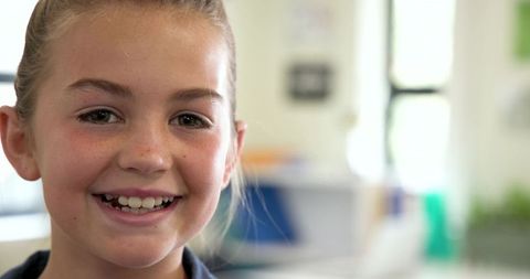 Cheerful young girl smiling brightly in classroom