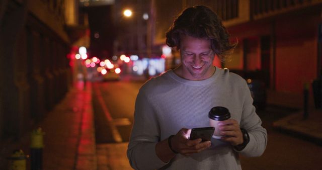 Man Walking at Night Using Smartphone and Holding Coffee - Download Free Stock Images Pikwizard.com