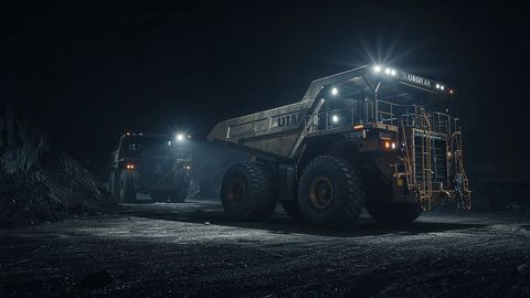Heavy dumper trucks operating at night in mining quarry