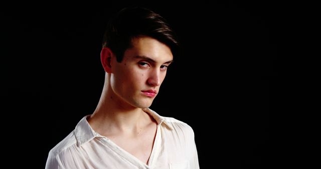 Young Man with Serious Expression in White Shirt Against Black Background - Download Free Stock Images Pikwizard.com