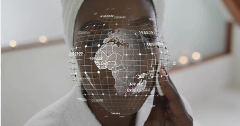 Applying cotton pad while cleansing face with ar holographic globe overlay, towel turban