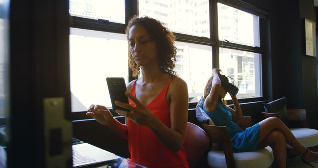 Woman Using Smartphone While Working on Laptop in Modern Office - Download Free Stock Images Pikwizard.com