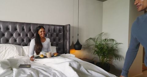 Smiling Woman Receiving Breakfast in Bed in Cozy Bedroom