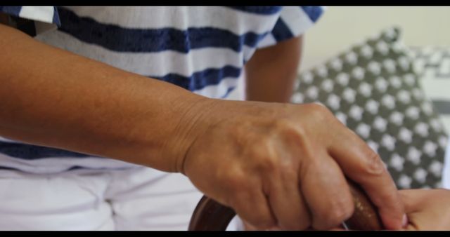 Close-up shot of caregiver helping senior with walking cane, ideal for use in healthcare, elderly care, support services, and assisted living brochures and websites.