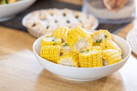 Buttered Corn Rounds Garnishing with Chopped Parsley in White Bowl on Wooden Table