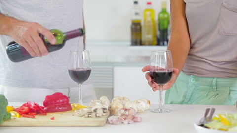 Couple Enjoying Red Wine During Meal Preparation