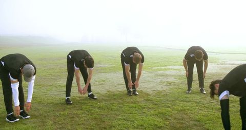 Athletes Stretching in Misty Outdoor Field Preparing for Team Activity