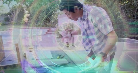 Teen leaning at patio table using tool, wearing checked shirt and beanie, holographic tech overlay
