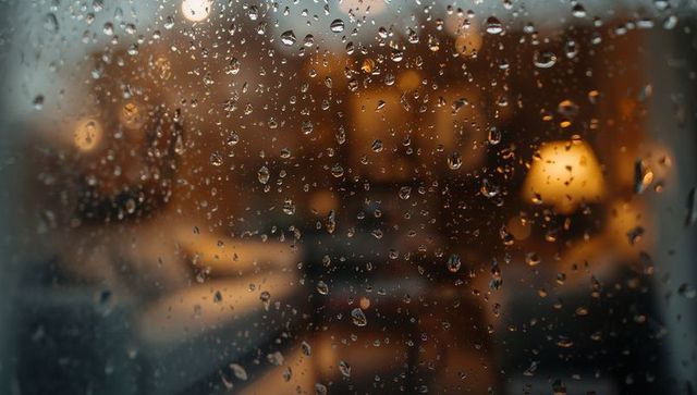 Rain-covered window with warm cozy interior view