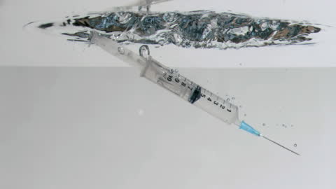 Syringe Immersed in Water in Slow Motion with Minimalist Background