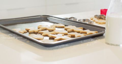 Unbaked sugar cookie shapes on baking sheet in home kitchen