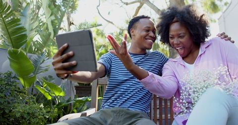 Cheerful Couple Taking Outdoor Selfie with Tablet in Sunny Garden