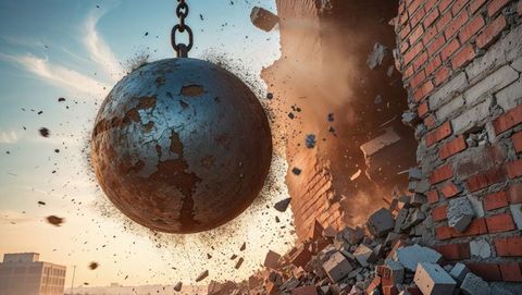 Rusted wrecking ball demolishing brick wall at urban construction site