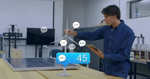 Engineer adjusting wind turbine prototype with tablet and solar panel notification badge