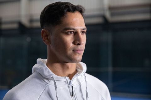 Pensive young man standing in indoor sports facility wearing white zip-up hoodie