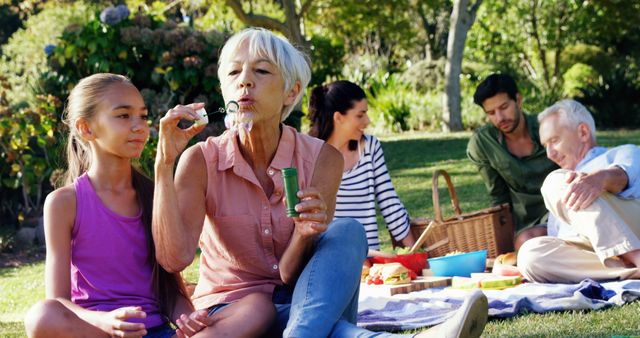 Grandmother Blowing Bubbles with Granddaughter at Family Picnic in Park - Download Free Stock Images Pikwizard.com