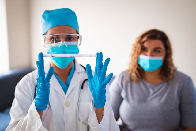 Biracial female doctor wearing face mask and surgical gloves holding covid 19 swab test. medicine and healthcare services during covid 19 pandemic.