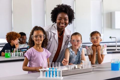 Black science teacher guiding elementary students during hands-on lab experiment