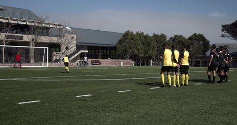 Soccer penalty kick with players watching on school field