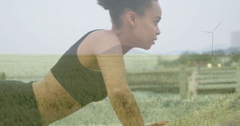 Active Woman Exercising in Scenic Grassland with Wind Turbines