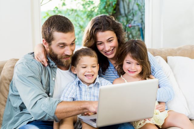 Smiling family with laptop sitting on sofa