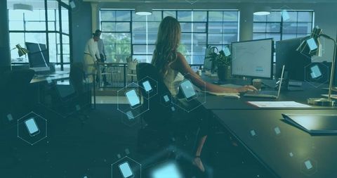 Working businesswoman using dual screens in modern open-plan office with ui overlays