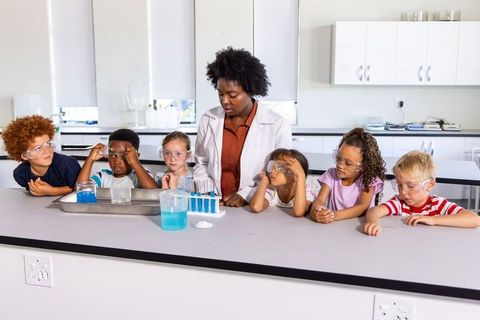 African american teacher guiding diverse children through hands-on science experiment