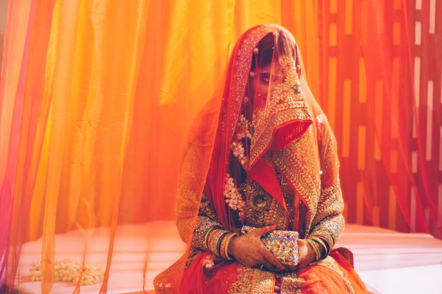 This vibrant image depicts a traditional Indian bride dressed in a richly decorated red outfit, accentuated by intricate jewelry and a veil. Ideal for use in wedding-related content, cultural blog posts, or articles about traditional Indian celebrations.