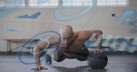 Shirtless athlete performing medicine ball pushup with ar fitness data overlay indoor gym