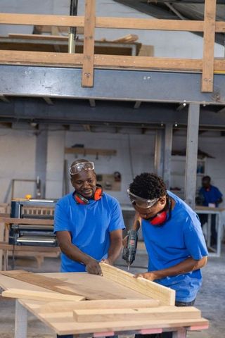 African american carpentry team working together drilling and assembling wood on workbench
