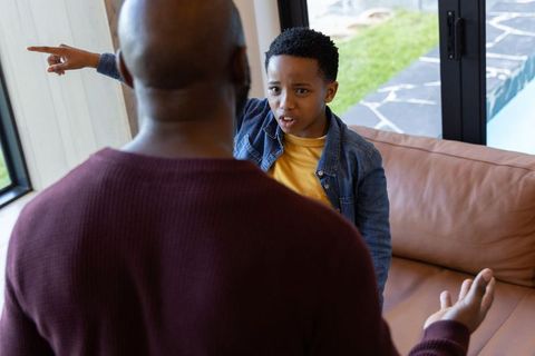 African american father and son arguing in living room pointing in intense family conflict