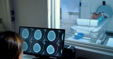African american technologist monitoring brain scans while patient undergoes mri scan