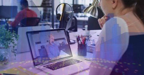 Businesswoman attending remote video meeting in open-plan office with digital overlays