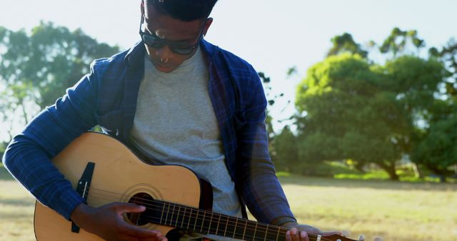A young man is playing an acoustic guitar outdoors, with copy space - Download Free Stock Photos Pikwizard.com