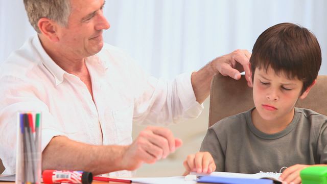 This portrayal of a grandfather patiently helping his grandson with academics embodies nurturing and bonding sentiments, ideal for use in educational or family-focused content, promoting themes of support and intergenerational connection.