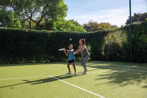 Mother and daughter enjoy tennis coaching on sunlit court